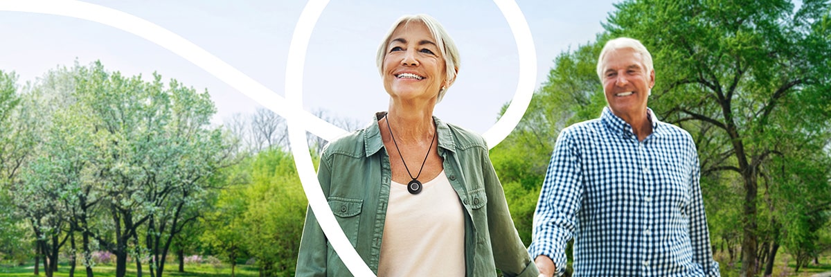 Woman wearing PERS walking in park with husband