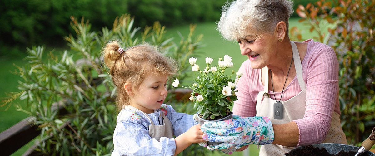 Woman wearing mobile PERS gardening with her granddaughter